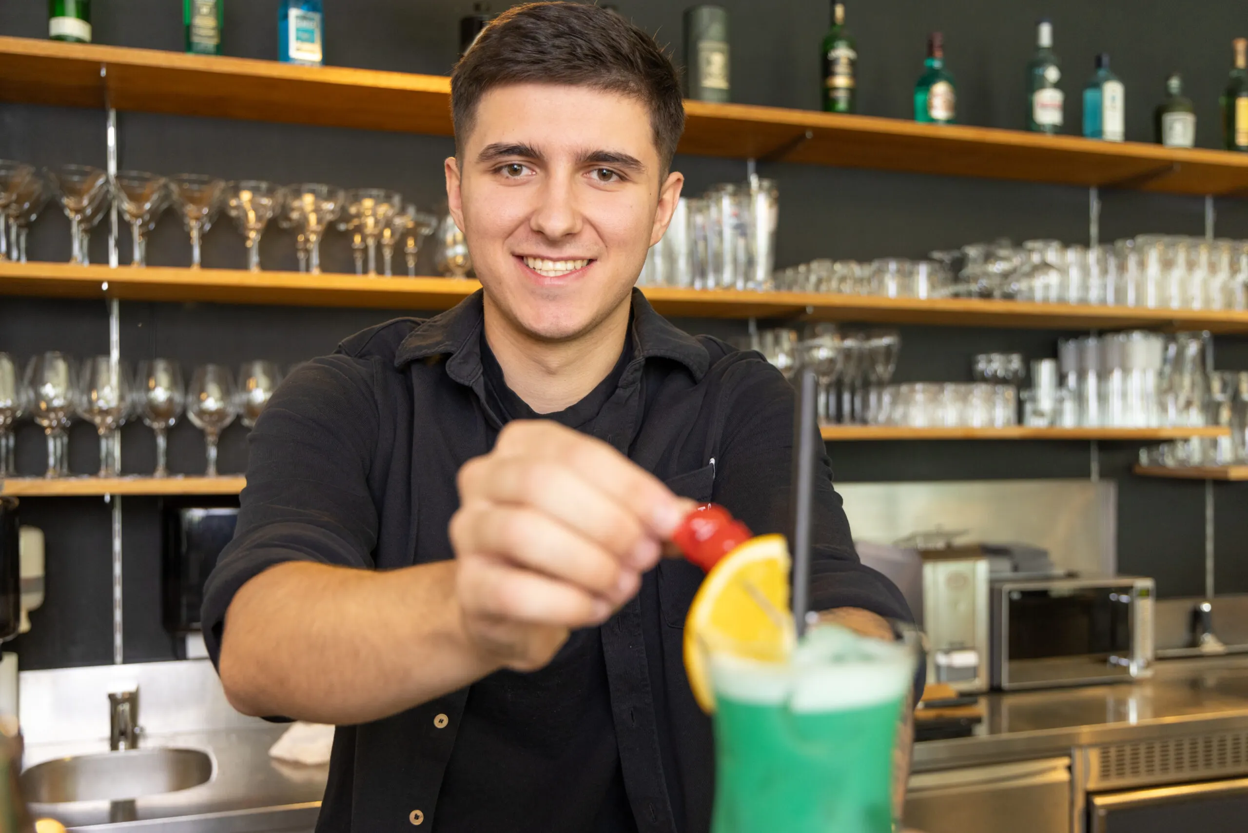 Barkeeper reicht einen grünen Cocktail