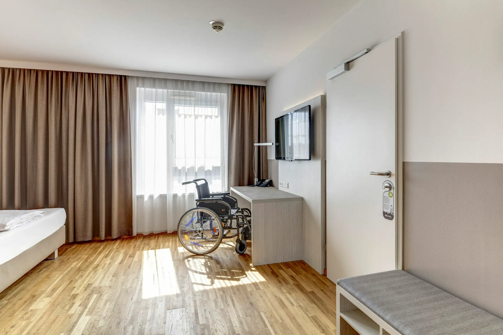 Accessible room: desk with wheelchair, wall-mounted TV and wide room door