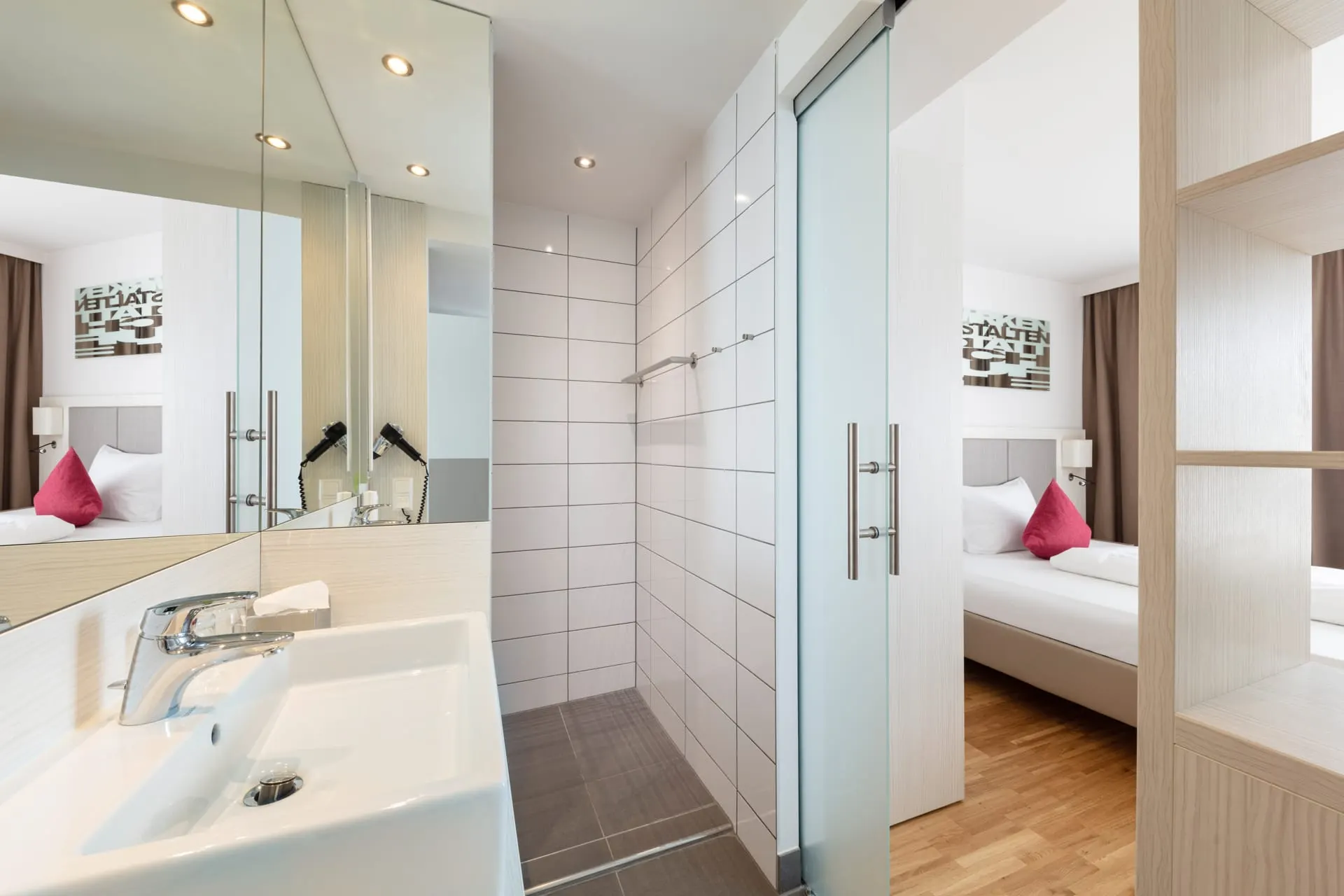 Zimmer City: Waschbecken und Dusche hinter Glas, getrennt vom Schlafbereich