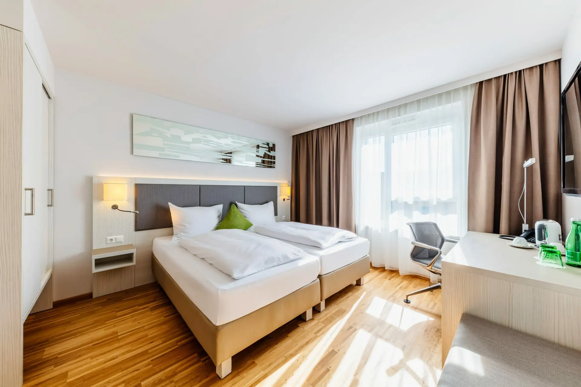Deluxe room: double bed, desk and bright wall of windows