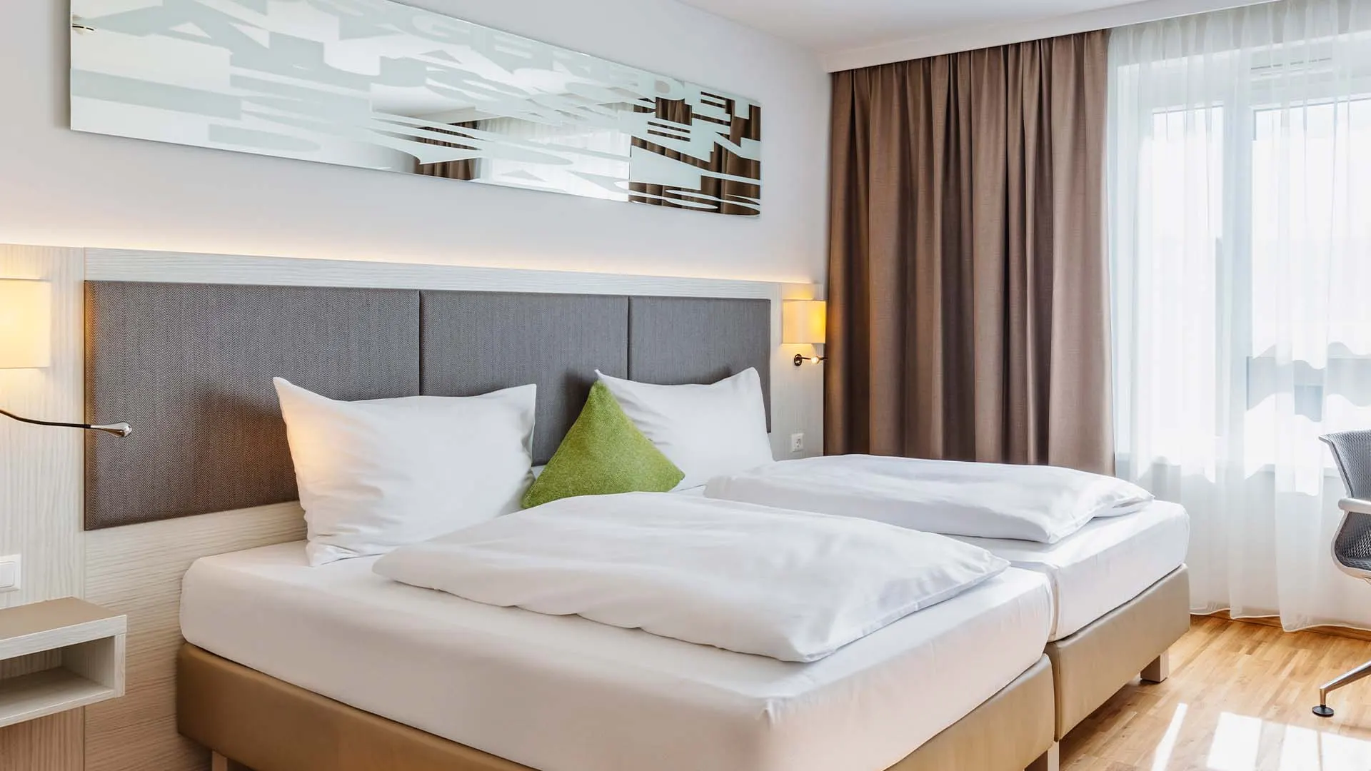 Frisch gemachtes Bett mit grünem Kissen