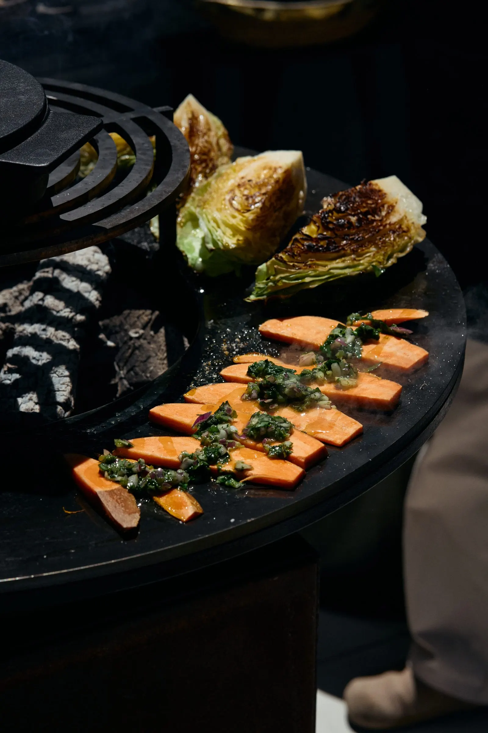 Gegrillte Süßkartoffeln mit Kräutern und Kohl auf der Kochplatte des OFYR